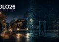 Cena urbana do YOLO26 com um ônibus e quatro pedestres delimitados por caixas únicas, em transição da imagem real para a detecção end-to-end